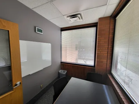 An east facing photograph of Study Room 202, featuring the table, 3 chairs, and whiteboard.