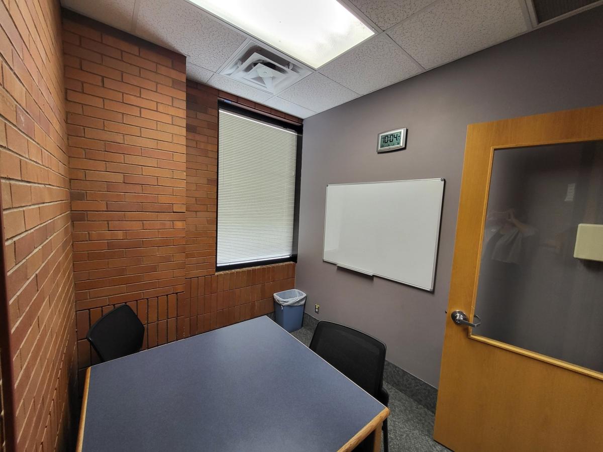 An east facing photograph of Study Room 200, featuring the table, 3 chairs, and whiteboard.